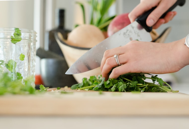 Hands chopping fresh coriander with a chef's knife